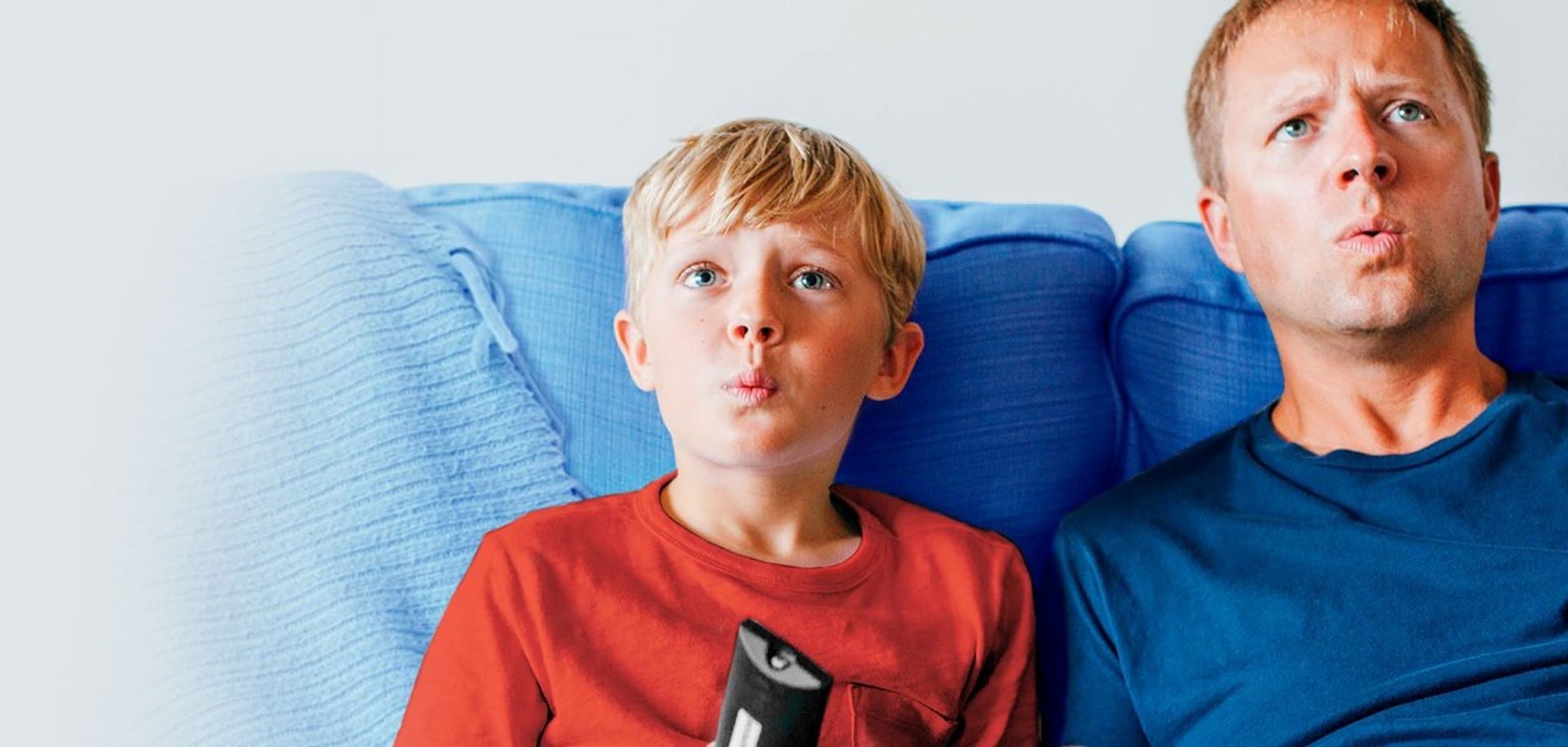 NetTV über Internet HD-Sender Vater und Sohn, der Fernbedienung in der Hand hält, sitzen auf einer Couch und sehen erstaunt aus