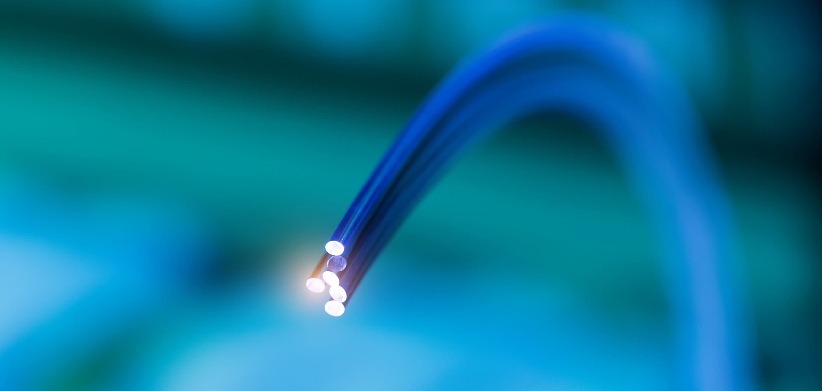 Mehr zu FTTH Ausbau Grünblauer Hintergrund mit Glasfaserkabeln