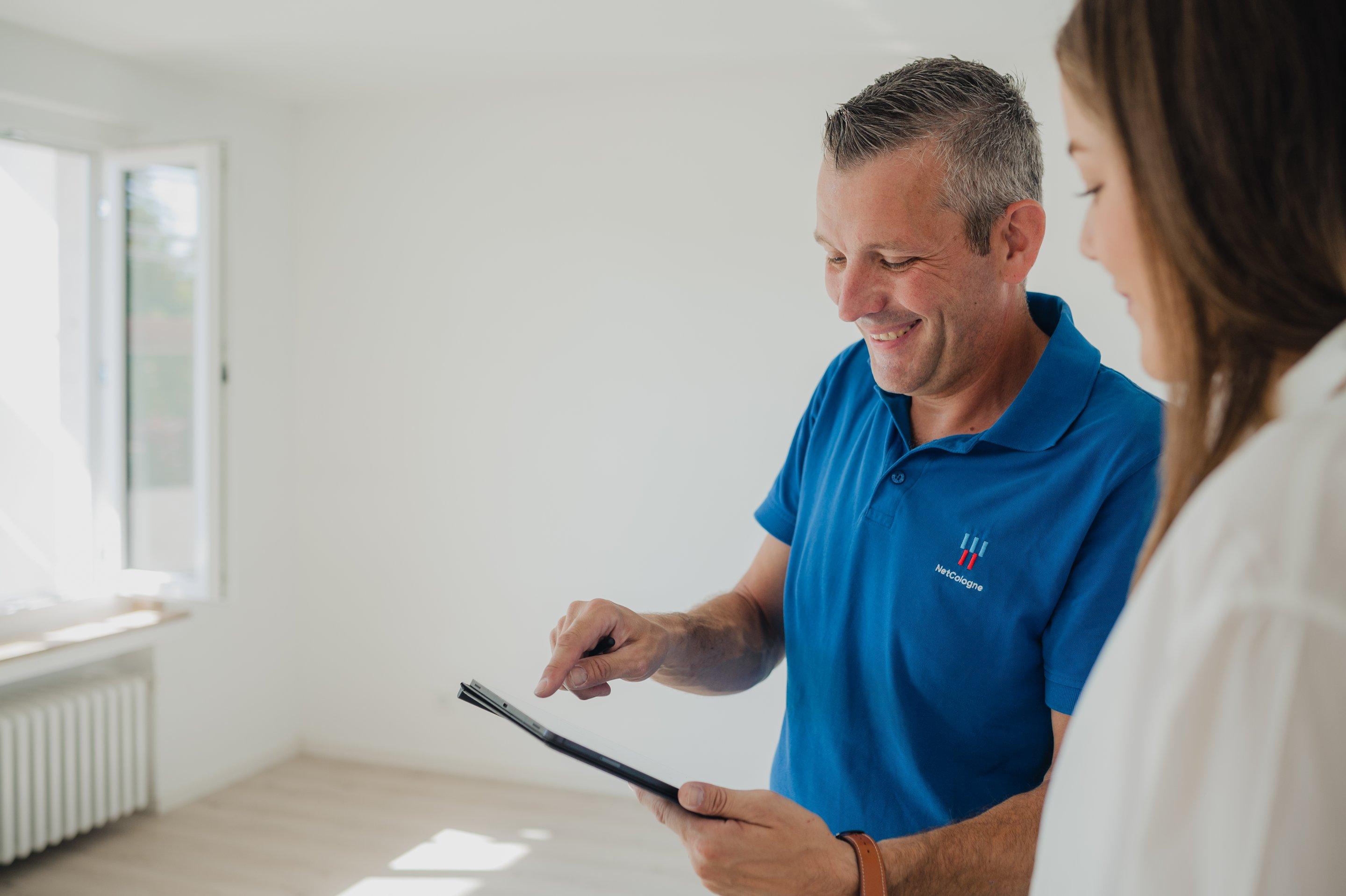 NetCologne Techniker mit einem Tablet in der Hand klärt Kundin über den Ausbau auf