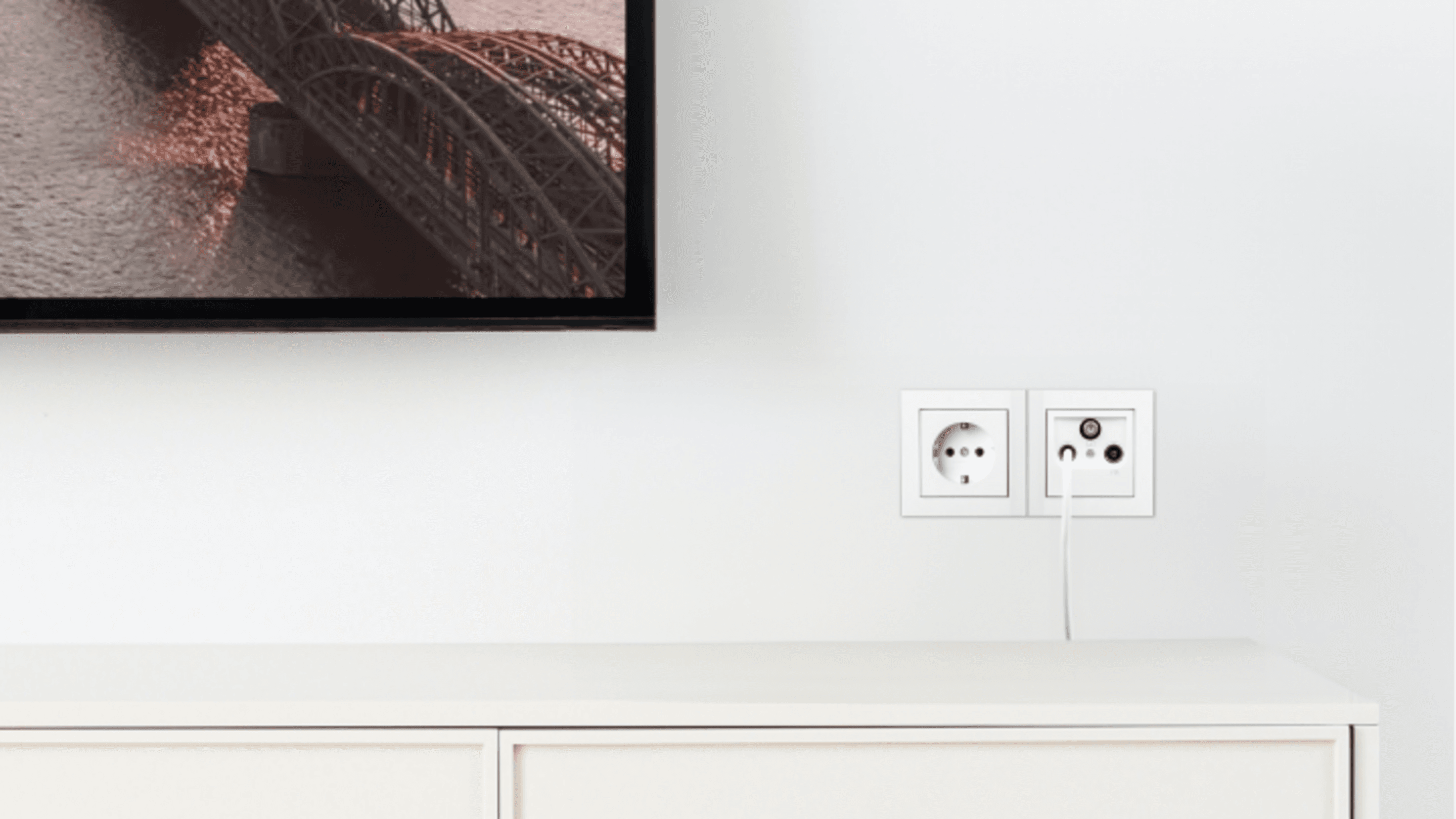 NetTV über Kabel Eine Wand an der ein Fernseher hängt, mit Steckdose und Kabel-Fernseheranschluss